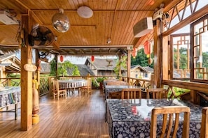 An indoor wooden dining area with tables and chairs, a wooden ceiling, and large windows. - Waiting For You at Yunshuiyao Inn (Nanjing County)