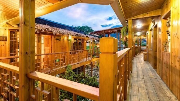 A wooden structure with a covered walkway, wooden railings, and a thatched roof visible in the background. - Waiting For You at Yunshuiyao Inn (Nanjing County)