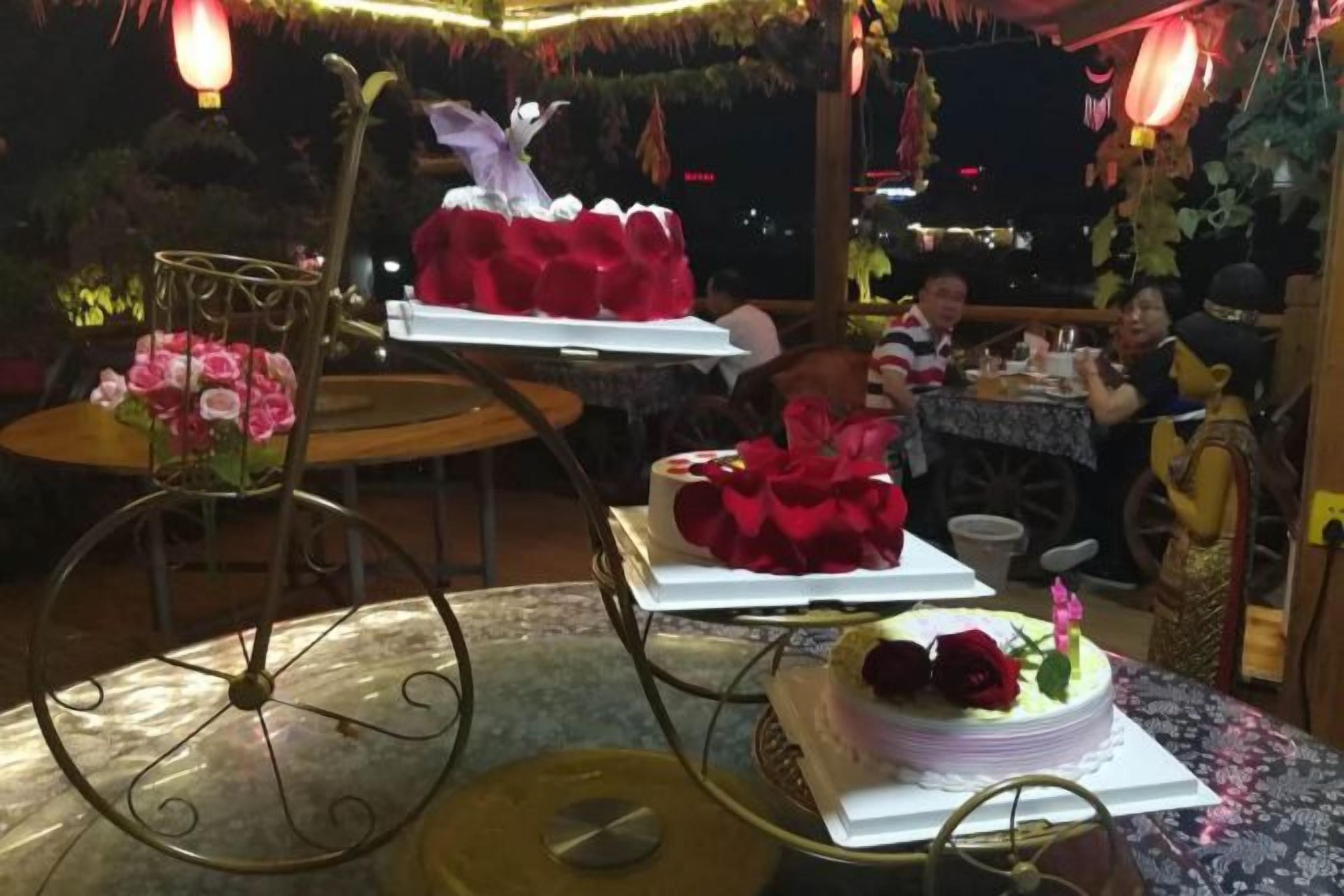 Un comedor con mesas y sillas, decorado con flores y un pastel sobre un soporte.