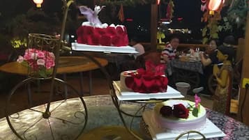 Un comedor con mesas y sillas, decorado con flores y un pastel sobre un soporte.
