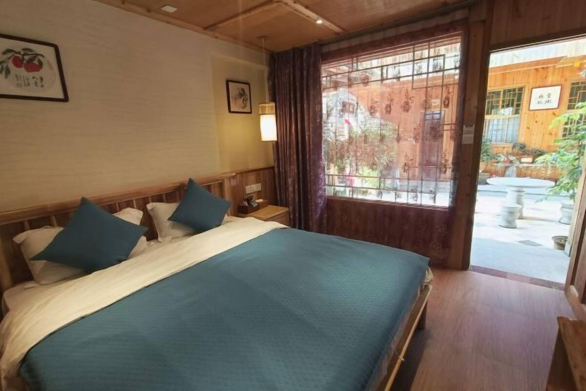 A room with a bed, a nightstand, a window with curtains, and a door leading outside.