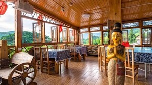 A restaurant with wooden interiors, tables with blue tablecloths, and a statue. - Waiting For You at Yunshuiyao Inn (Nanjing County)