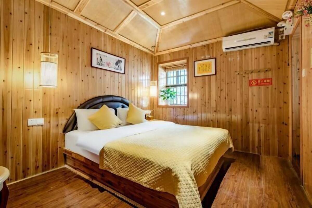 A wooden-paneled room with a bed, wall-mounted air conditioning, and framed artwork.
