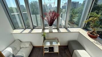 A modern room with a large window, a sofa, a small table, and a potted plant.
