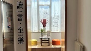 A room with a window, a table, and two chairs. There is a sign with Chinese characters on the wall.