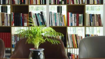 A bookshelf filled with books, a vase with a plant, and a chair.