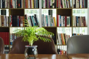 Una estantería llena de libros, un florero con una planta y una silla.