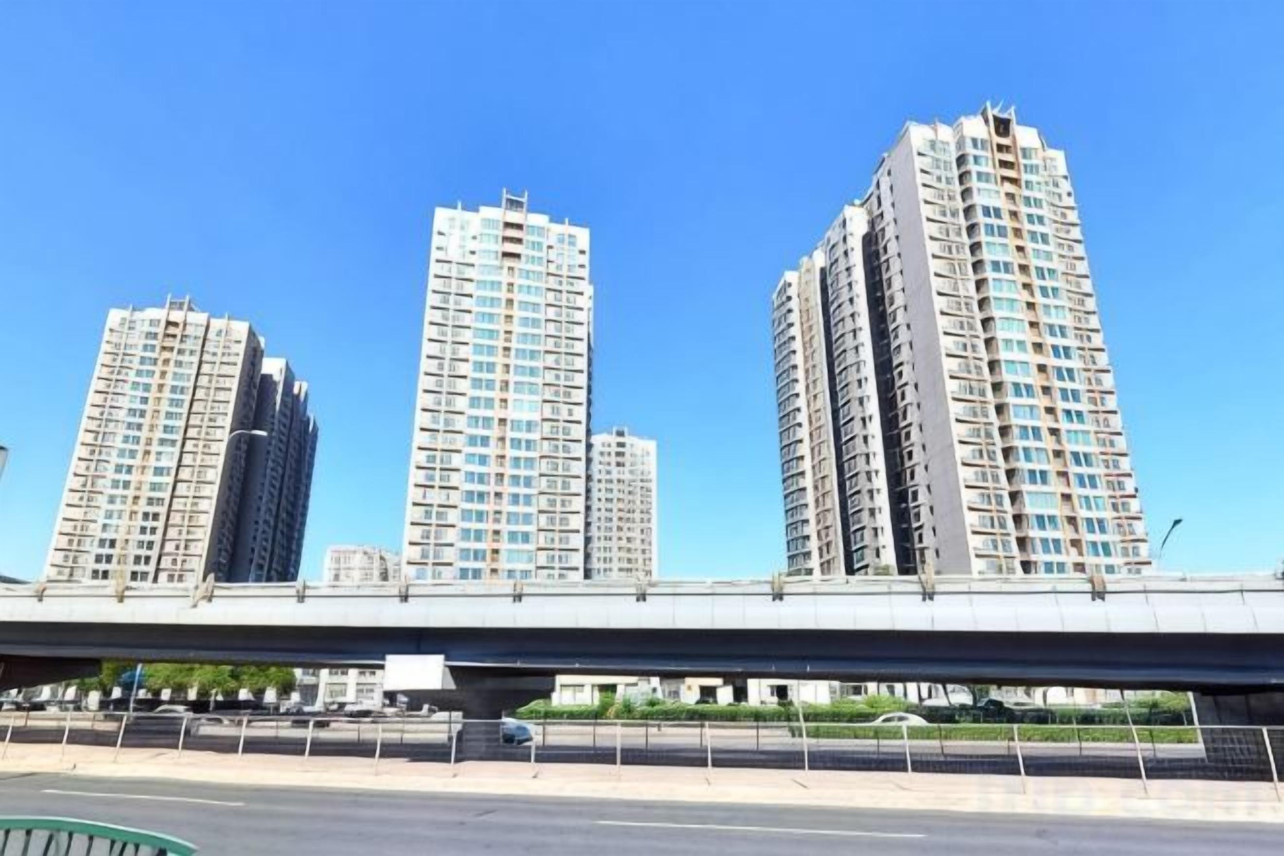 Un edificio de varios pisos con techo plano, situado cerca de un puente.