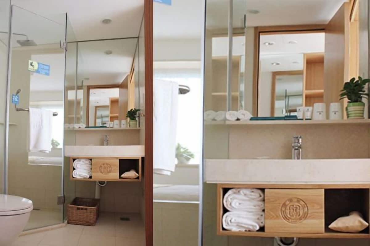 A modern bathroom with a glass shower enclosure, a wooden vanity with a mirror, and a towel rack.