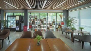 A modern library with bookshelves, seating, and a vending machine.