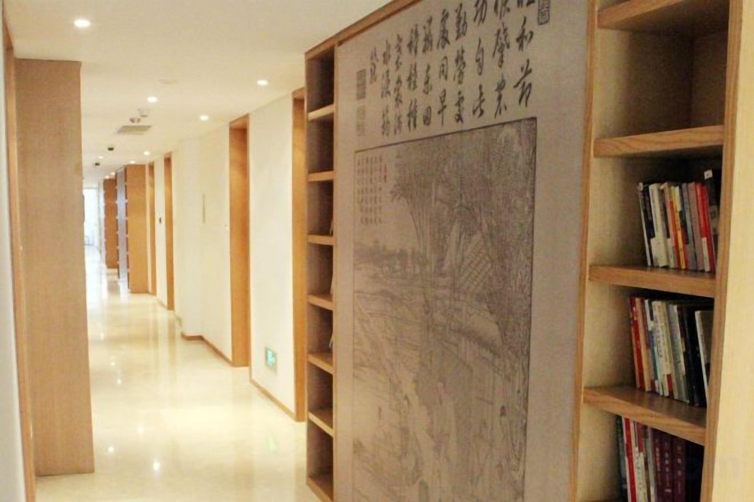 Un pasillo con estanterías a ambos lados, una gran pared con caligrafía y un interior limpio y moderno.