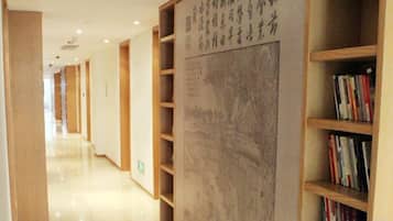 Un pasillo con estanterías a ambos lados, una gran pared con caligrafía y un interior limpio y moderno.