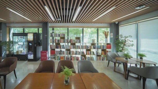 A modern library with a wooden ceiling, bookshelves, and seating areas.