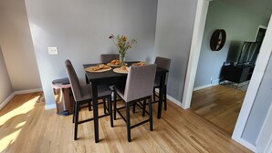 Et spiseområde med et sort bord, seks grå stole og en vase med blomster.