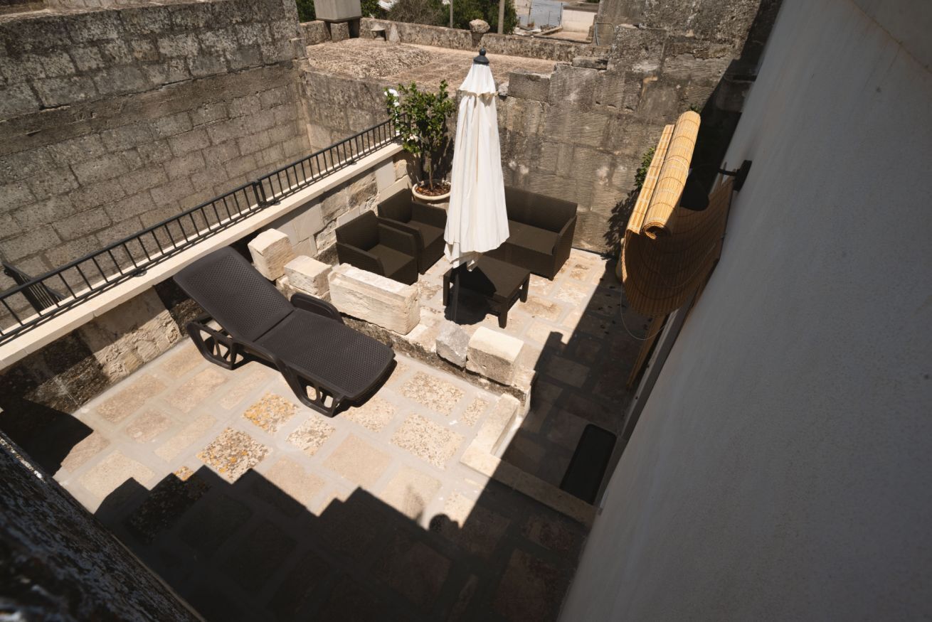 Terraza en la azotea con mobiliario exterior, una planta en maceta y un paraguas blanco.