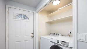 A laundry room with a white door, a washing machine, and a dryer. - NEW! Charming Duplex - Central, Ski, Hike, Unwind! (Sandy)