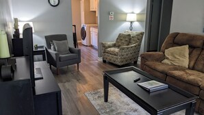 Een woonkamer met een bank, fauteuil, salontafel en een televisie.