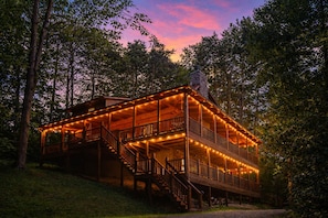 A wooden cabin with a balcony, surrounded by trees.