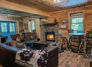 L’intérieur d’une cabane en rondins, avec une cheminée en pierre, des meubles en bois et une porte bleue.