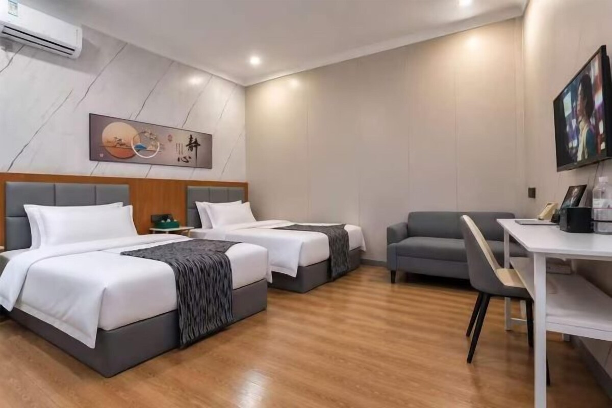 A hotel room with two beds, a desk, and a chair.