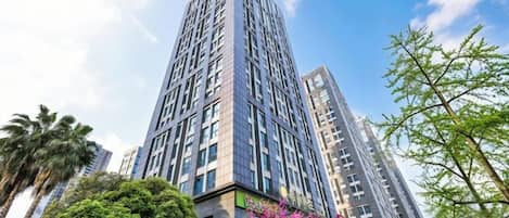 A high-rise building with multiple floors, surrounded by greenery and other tall structures.