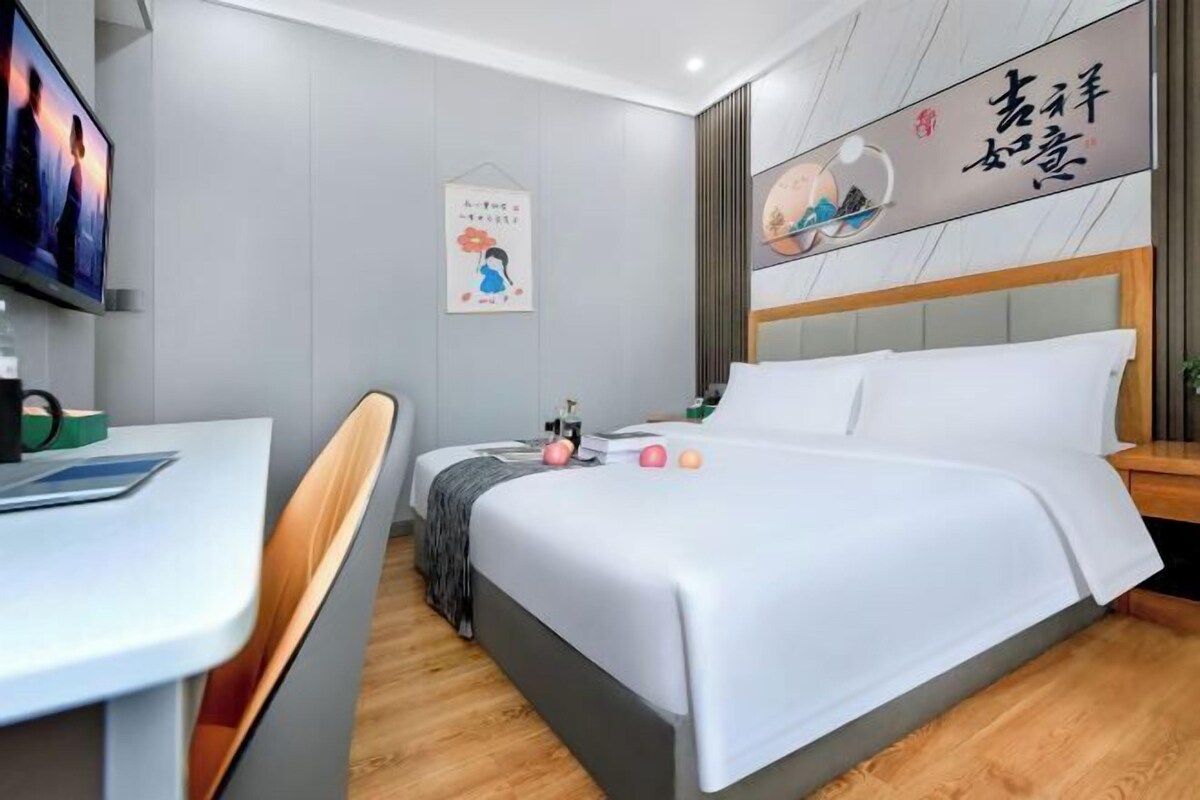 Habitació d'hotel moderna amb llit, escriptori i televisió.