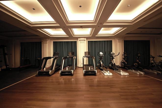 Amplia habitación con suelo de madera, equipada con varias cintas de correr y bicicletas estáticas.