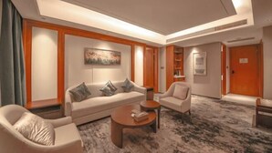 A modern hotel room with a sofa, armchairs, a coffee table, and a carpeted floor. - Huayun Hotel (Yushan)