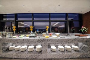 A buffet setup with various food items and stacked plates. - Huayun Hotel (Yushan)