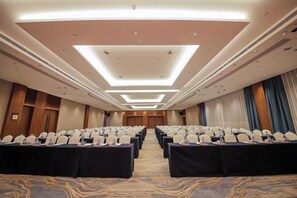 A conference room with rows of tables and chairs, a carpeted floor, and a modern ceiling design. - Huayun Hotel (Yushan)
