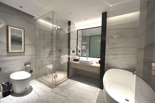 Un baño moderno con ducha envuelta en vidrio, inodoro independiente y bañera separada.