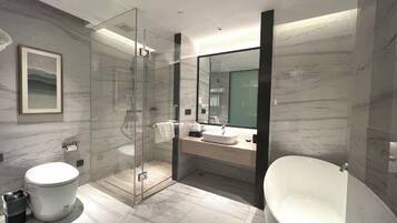 Un baño moderno con ducha envuelta en vidrio, inodoro independiente y bañera separada.