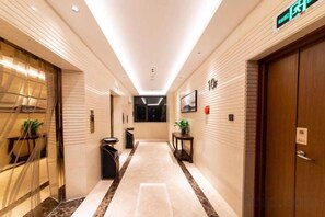 A hotel corridor with a reception desk, a trash bin, and a door with a sign. - Huayun Hotel (Yushan)