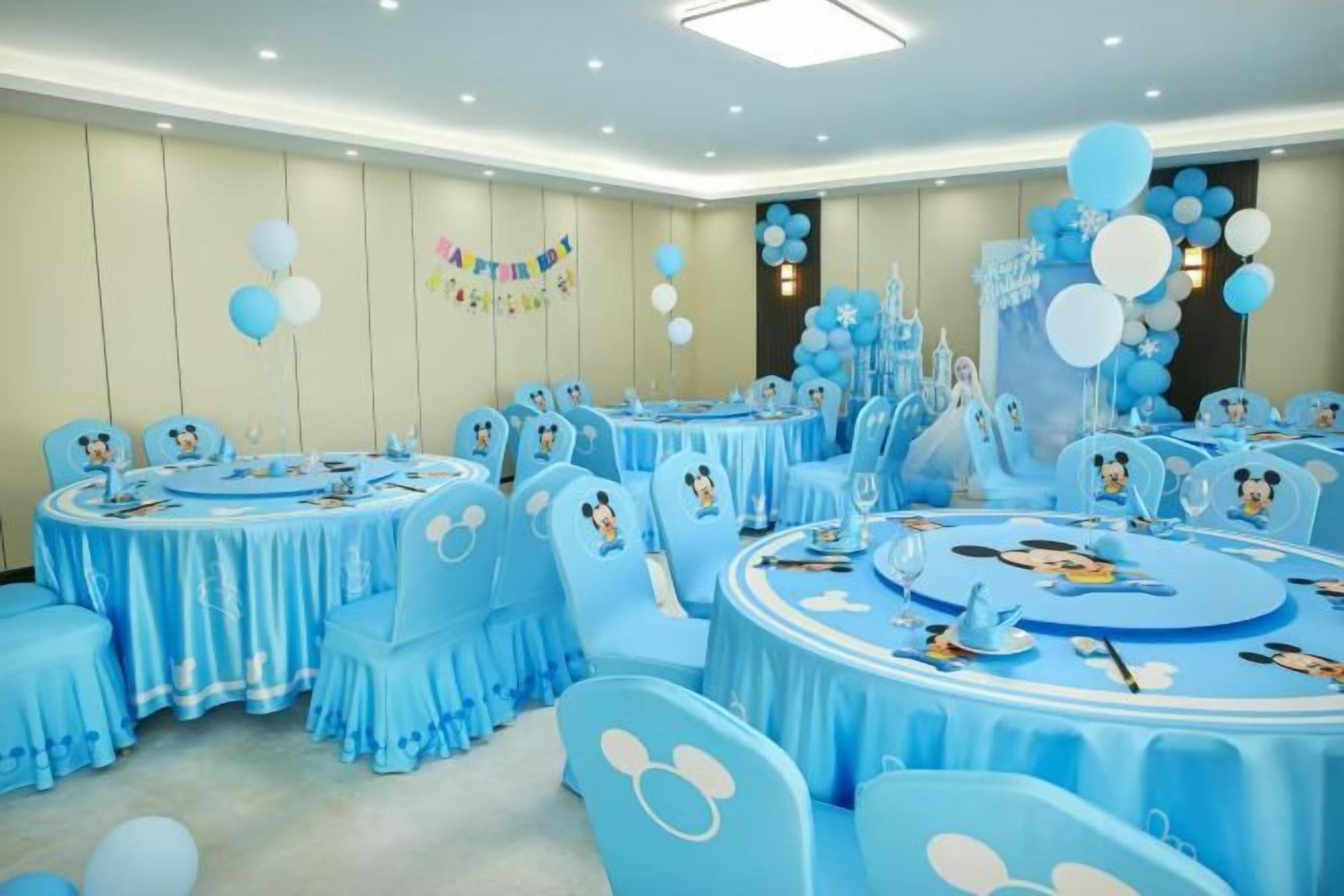 A room with multiple round tables, each with a Mickey Mouse theme, and matching chairs.