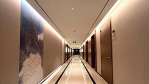 A long, narrow hotel corridor with a polished floor, wooden doors, and a large wall mural. - Huayun Hotel (Yushan)