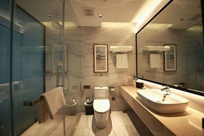 A modern bathroom with a glass shower enclosure, a toilet, a sink, and a large mirror. - Huayun Hotel (Yushan)