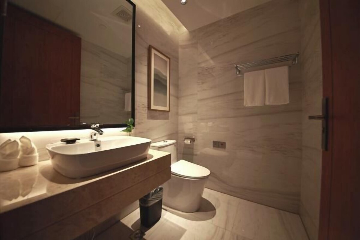 A modern bathroom with a large sink, toilet, and shower area.