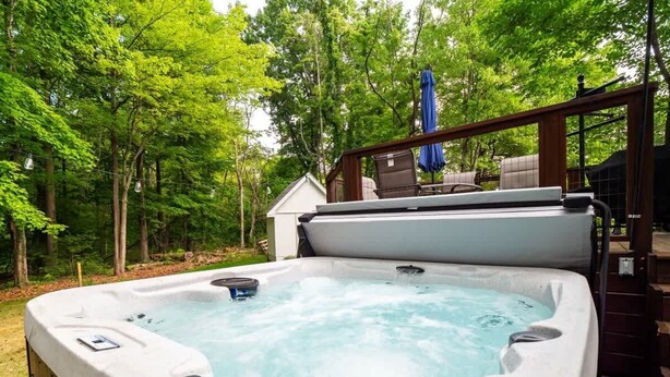 Ein Whirlpool in einem Garten mit einer Holzterrasse und einem Haus im Hintergrund.