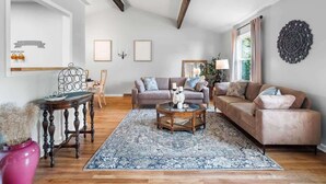 Ein geräumiges Wohnzimmer mit Holzboden, zwei Sofas, einem Couchtisch und einem dekorativen Spiegel.