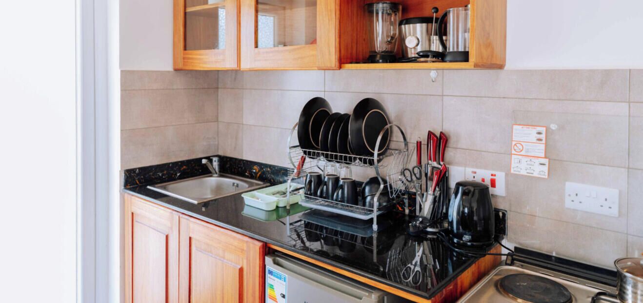 Una cucina con mobili in legno, un piano di lavoro nero, un espositore per piatti, una macchina da caffè e un bollitore.
