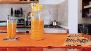 Eine Küche mit einem Tisch für zwei Personen, mit einer Kanne und Gläsern Orangensaft.