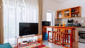 Ein modernes Wohnzimmer mit Flachbildfernseher, einer Holzbar und einem farbenfrohen Teppich.