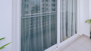 A balcony with large windows, a potted plant, and a tiled floor. - Beautiful ocean-view 2 bedroom home in Fumba Town (Fumba Town)