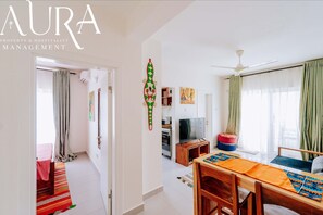 Una sala moderna con comedor, cocina y un dormitorio con cama y cortinas.