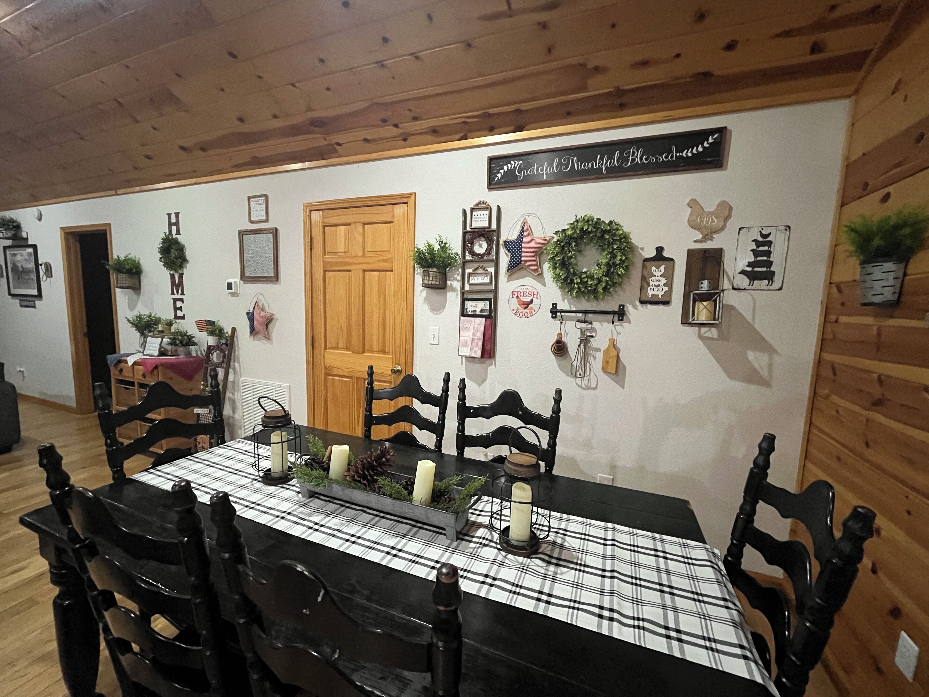 Ein Essbereich mit Holzboden, einer karierten Tischdecke und schwarzen Stühlen.