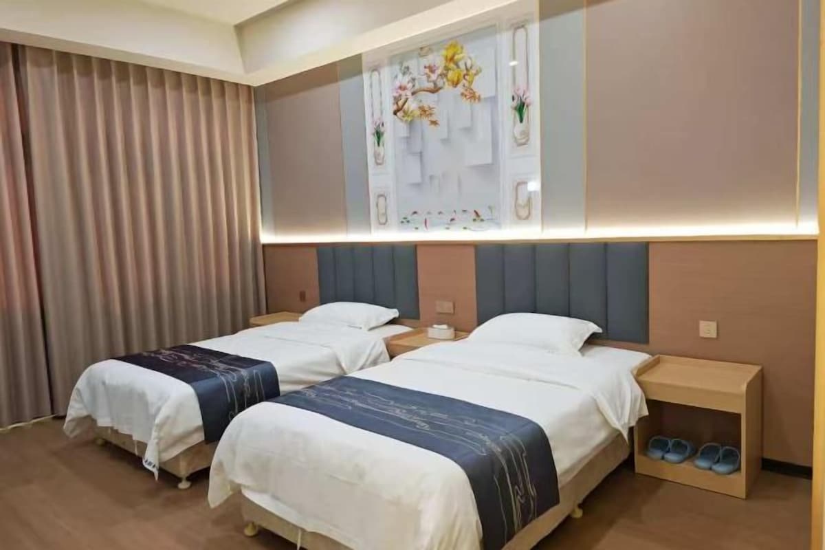 Habitación de hotel con dos camas, una mesita de noche, un espejo y un zapatero.