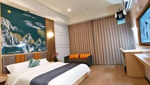A hotel room with a large bed, a desk, a television, and a painting on the wall. - Yueyan Business Hotel (Zhuhai)