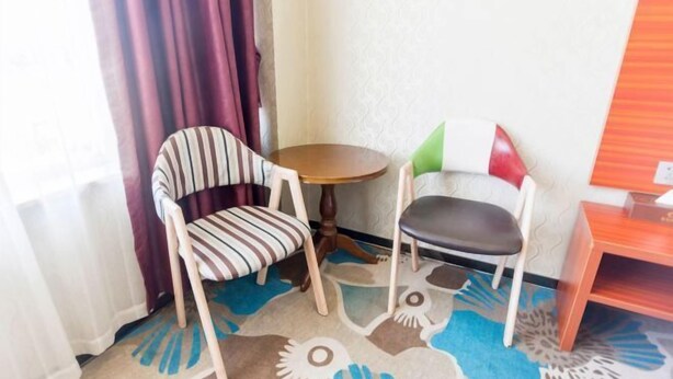 A small room with two chairs, a round table, and a wooden cabinet. - Yueyan Business Hotel (Zhuhai)
