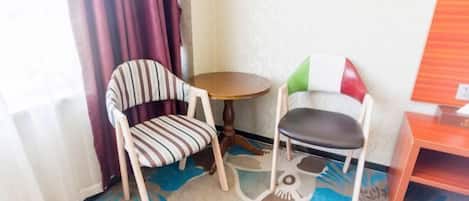A small room with two chairs, a round table, and a wooden cabinet.