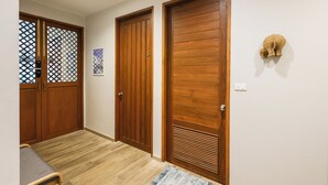 A hallway with wooden doors, a small table, and a rug. - Chiang Mai Colonial House (Tambon San Phi Suea)